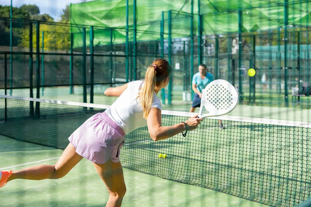 chica jugando a padel de espaldas con fondo hombre